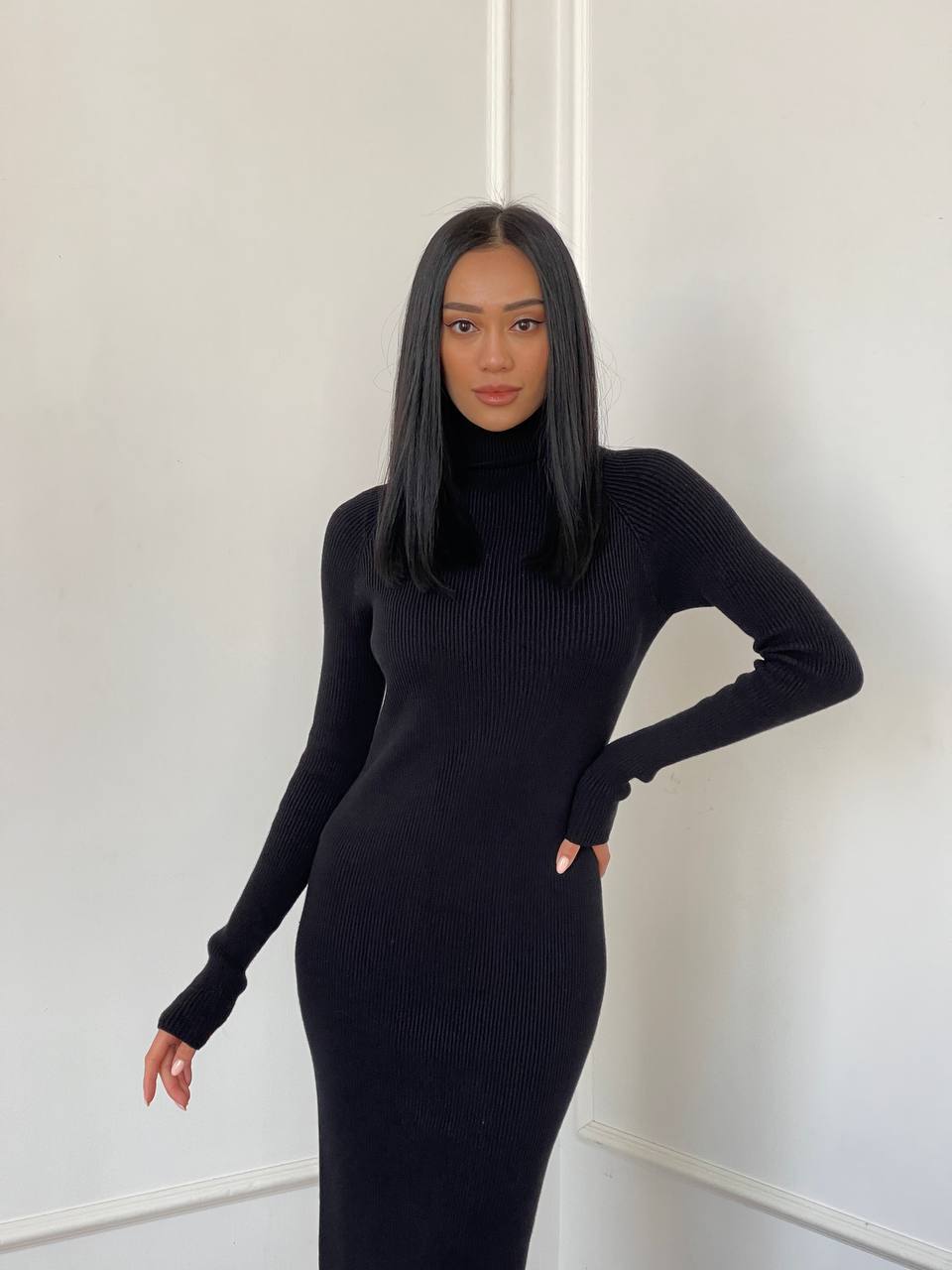 Person wearing a black ribbed dress against a white background