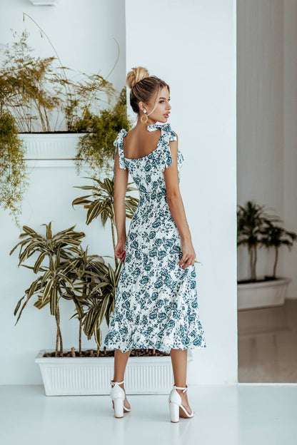 Woman in a floral dress standing in a room with plants