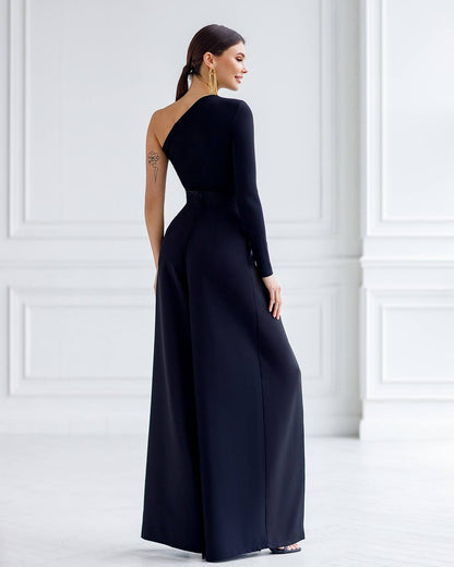 Woman wearing a one-shoulder navy blue gown against a white wall.