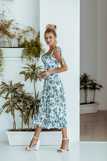 Woman in a floral dress standing in a room with plants