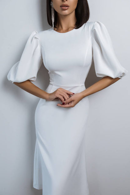 Woman wearing a white dress with puffed sleeves against a plain background