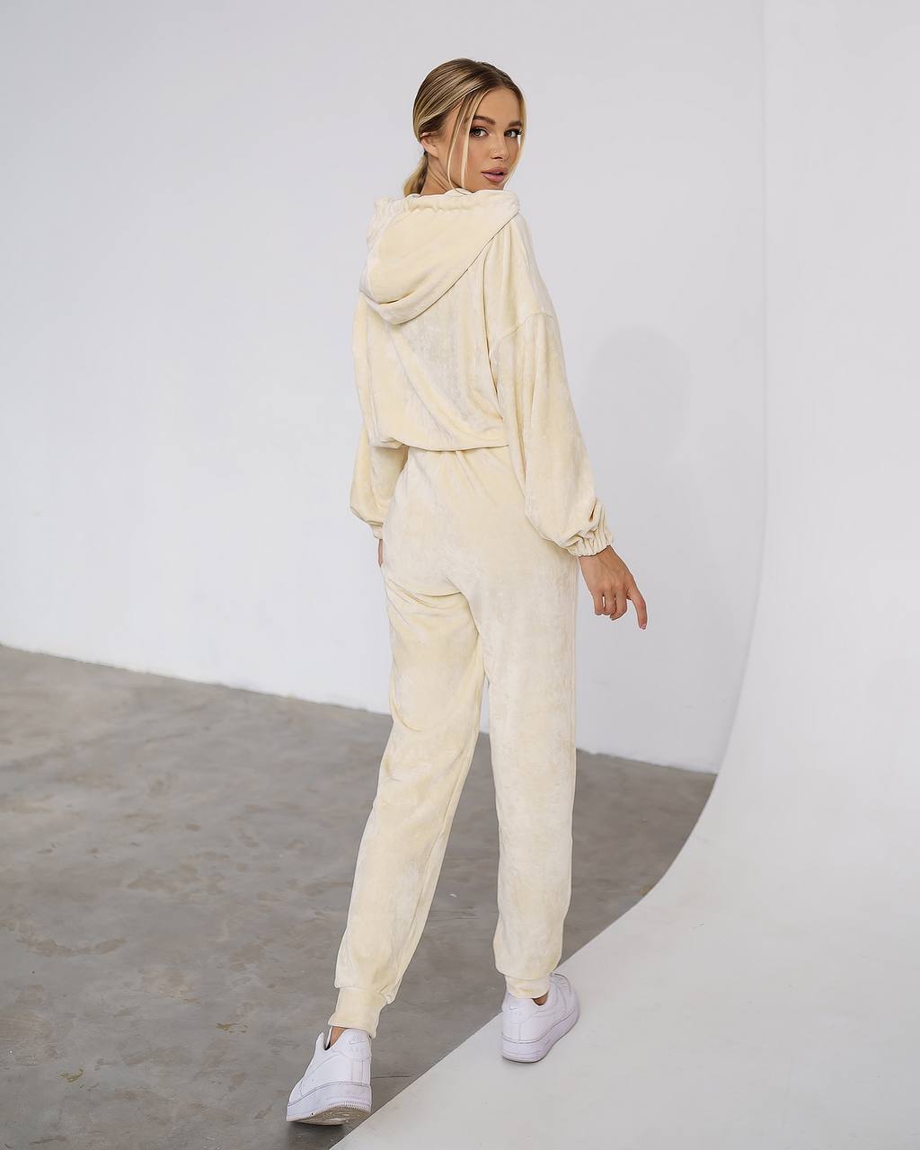 Woman wearing a beige tracksuit against a white background