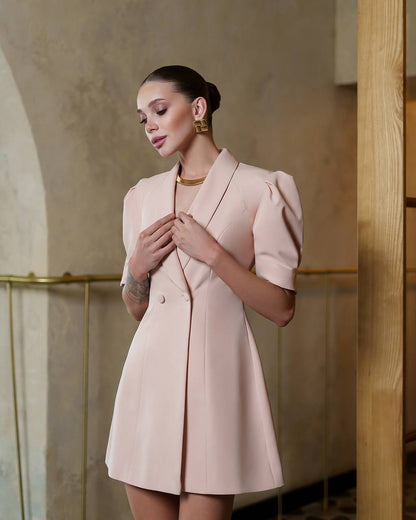 Woman wearing a light pink blazer dress in an elegant interior setting