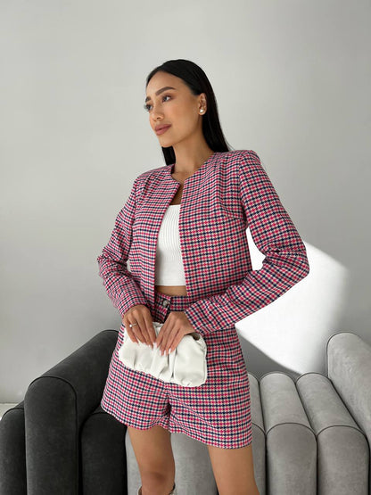 Woman wearing a pink plaid outfit sitting on a gray couch.