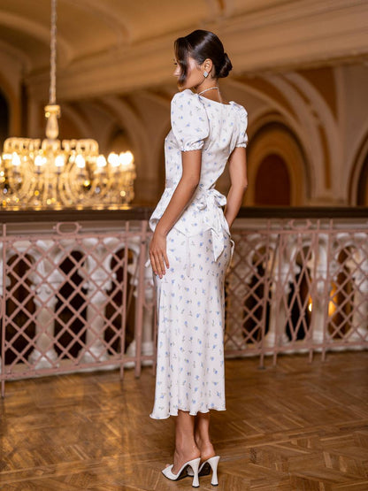 Woman in a white dress standing in an elegant indoor setting with chandeliers.