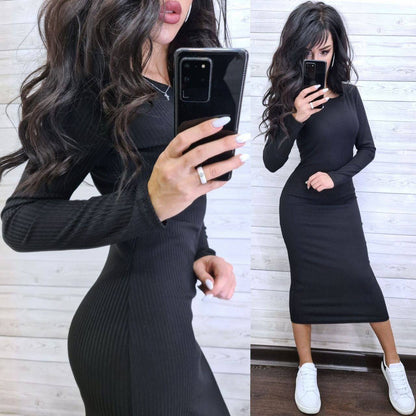 Woman taking a mirror selfie wearing a black long-sleeve dress with white sneakers.