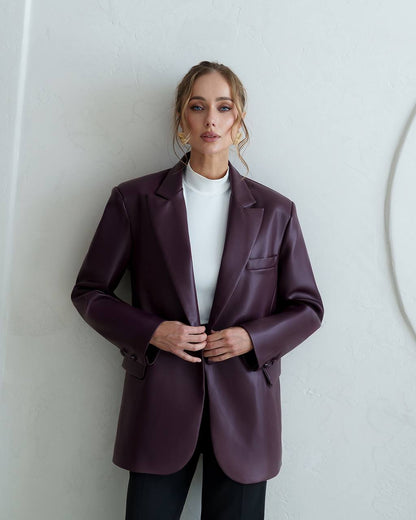 Woman wearing a purple blazer against a white wall