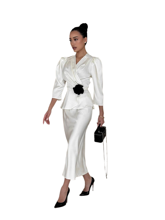 Woman wearing a white outfit with a black flower accessory on a white background