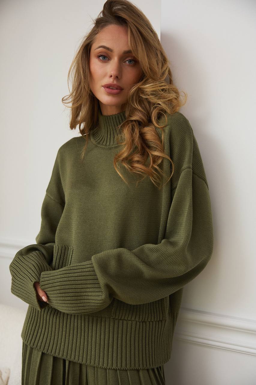 Woman wearing a green sweater against a white wall