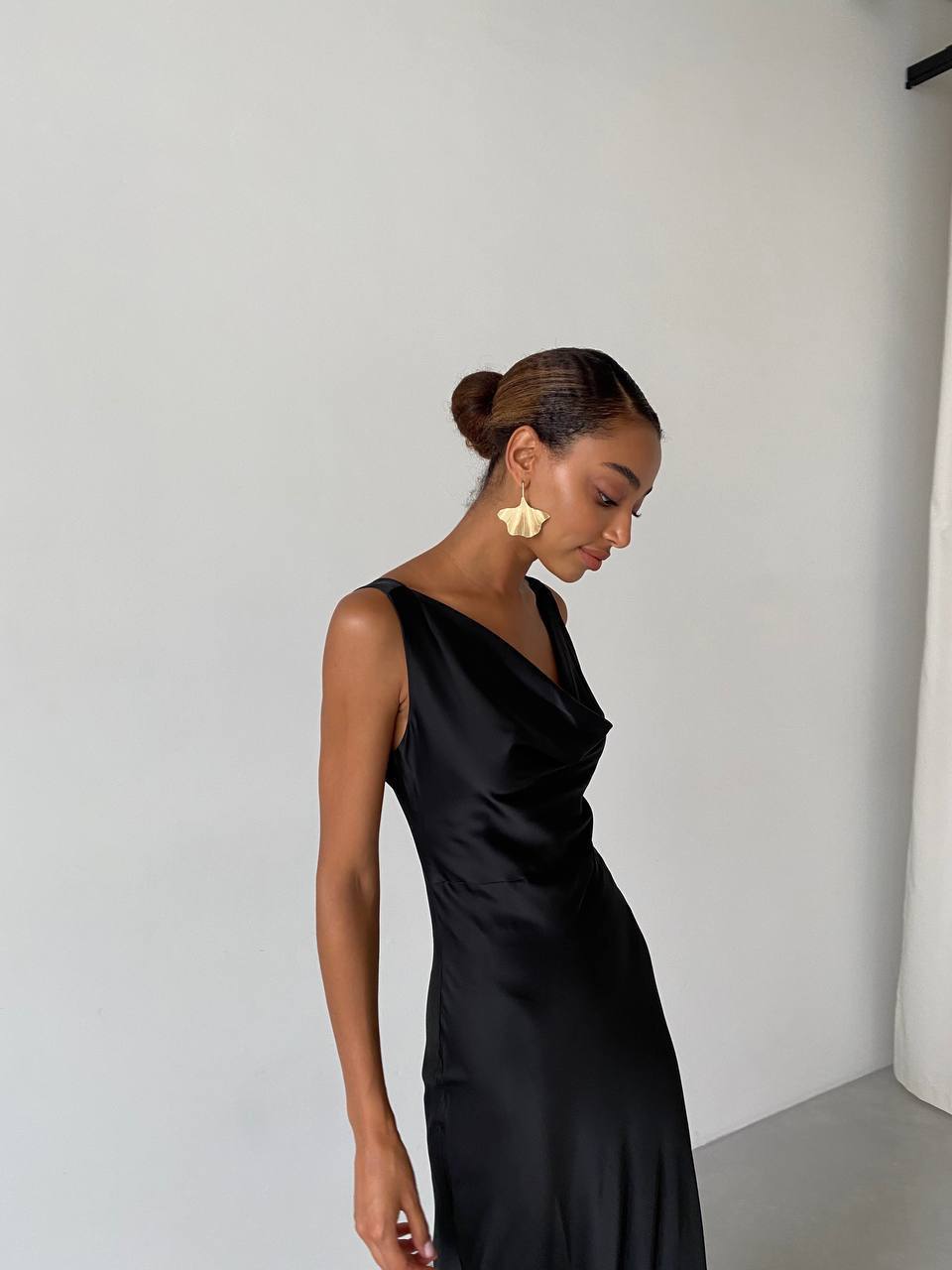 Woman wearing a black satin dress against a plain background