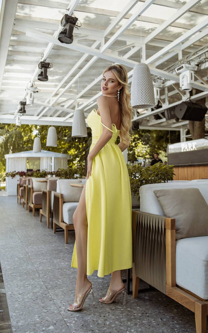 Woman in a yellow dress standing in an outdoor setting with chairs and tables.