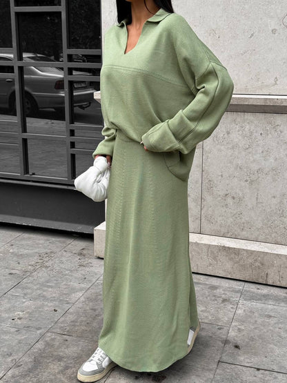 Person wearing a long green dress with white sneakers on a city street.