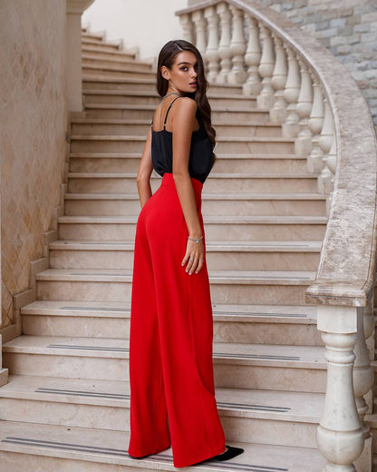 Woman in a black top and red pants standing on a marble staircase.