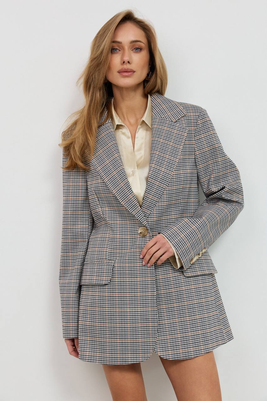 Woman wearing a checkered blazer over a white shirt on a light background