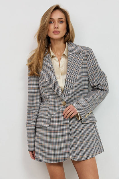 Woman wearing a checkered blazer over a white shirt on a light background