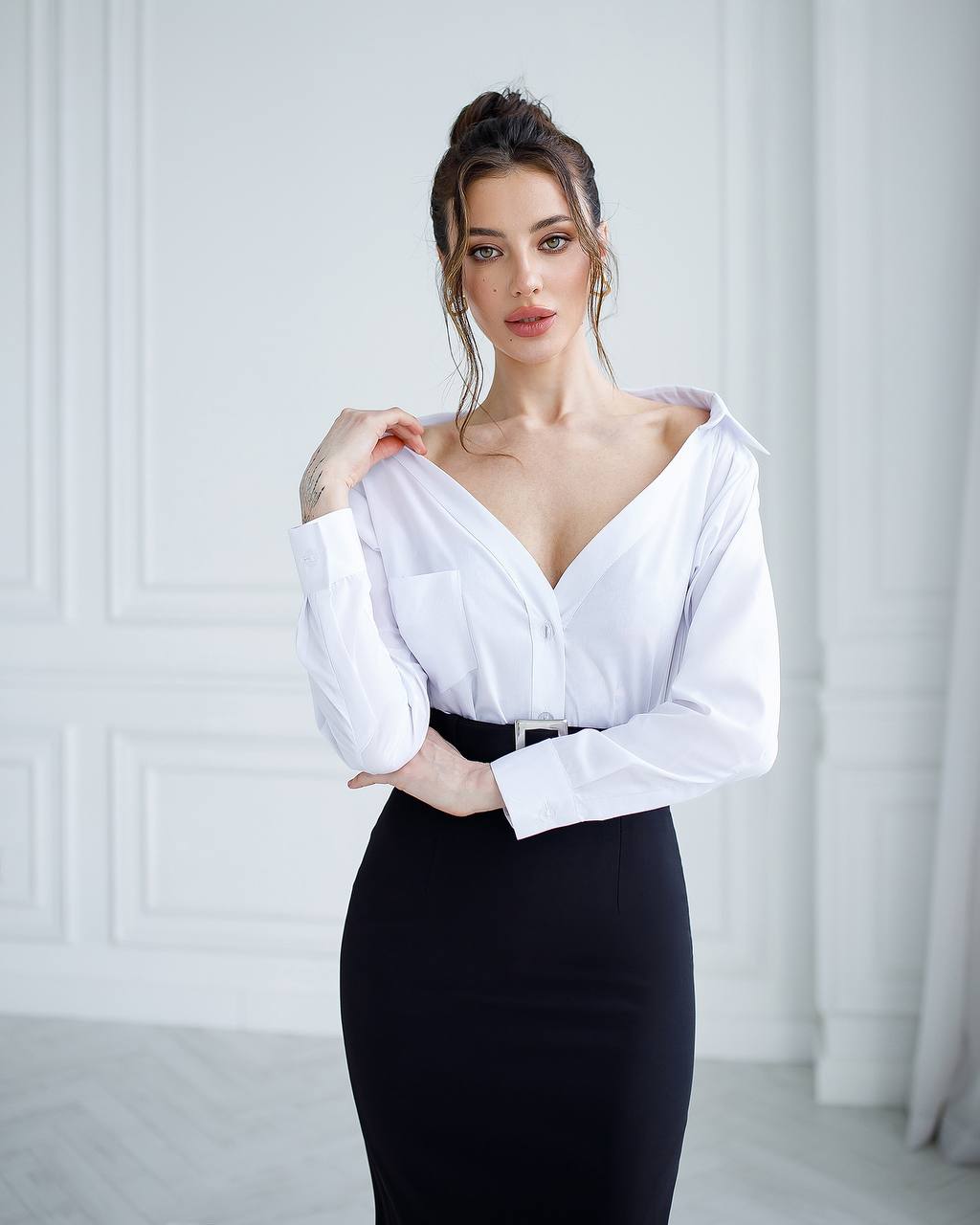 Woman wearing a white blouse and black skirt against a white background