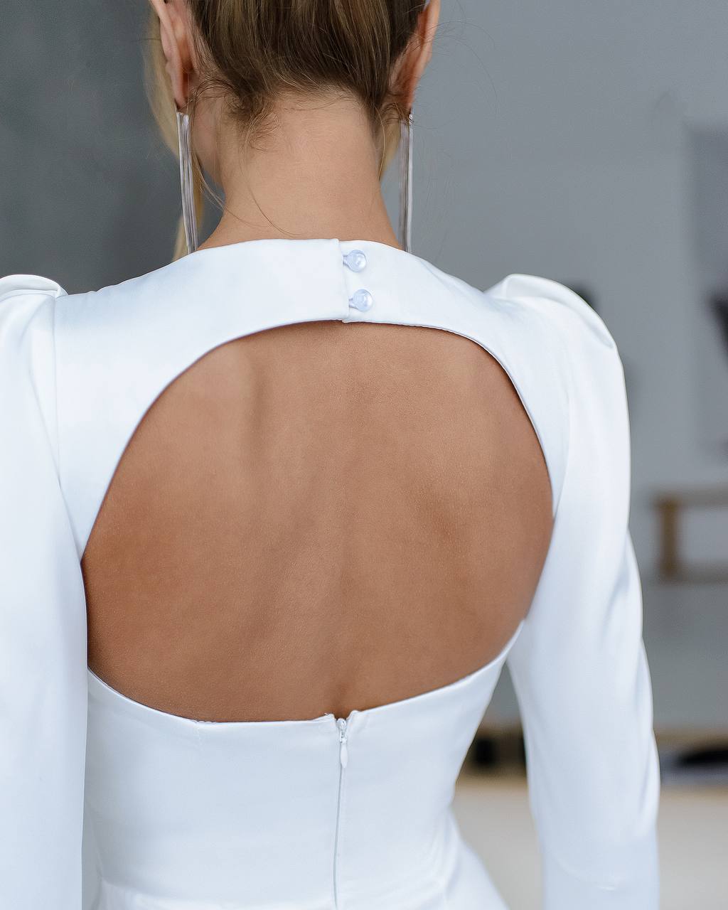 White long-sleeve top with open back worn by a person, blurred background