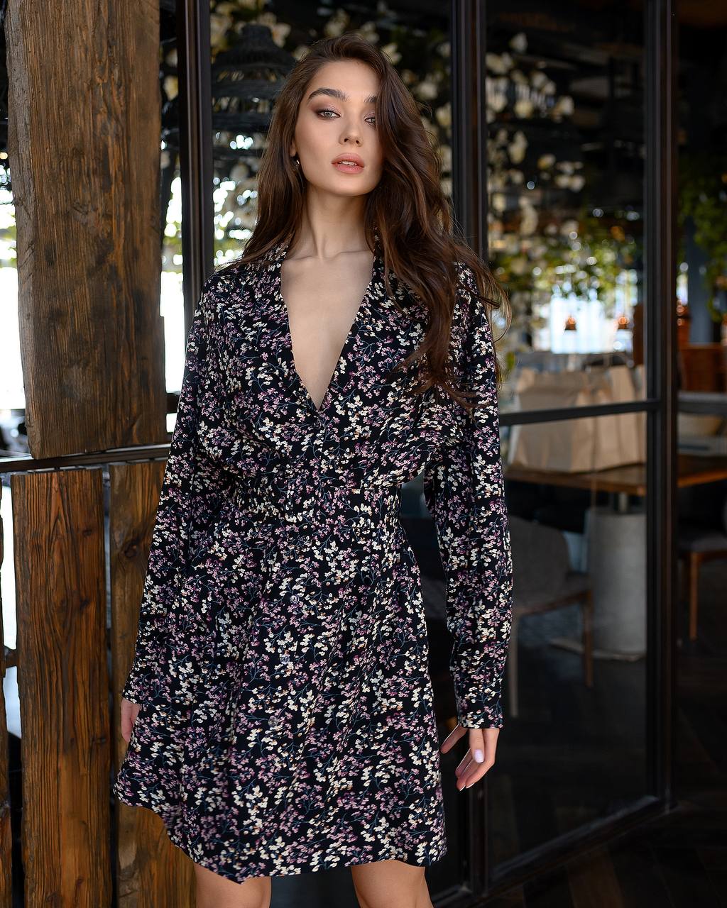 Woman wearing a floral dress standing in front of a restaurant entrance.