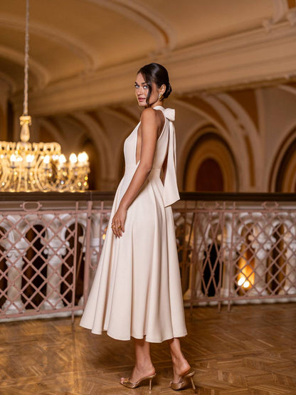 Woman in a white dress standing in an elegant indoor setting with chandeliers.