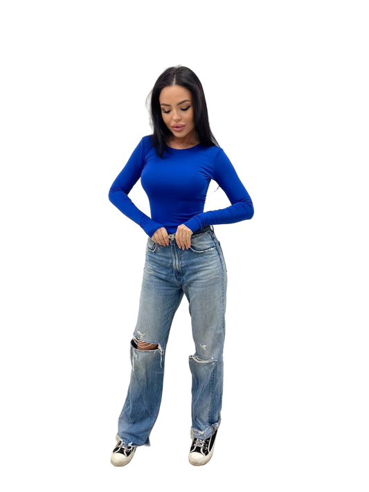 Woman wearing a blue top and ripped jeans on a white background