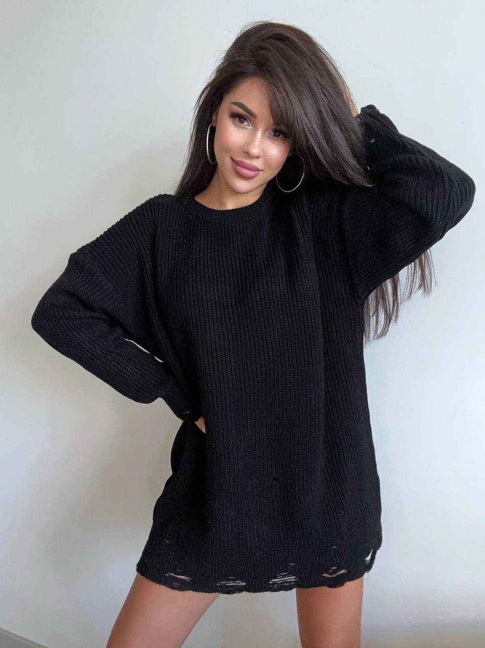 Woman wearing a black sweater against a plain background