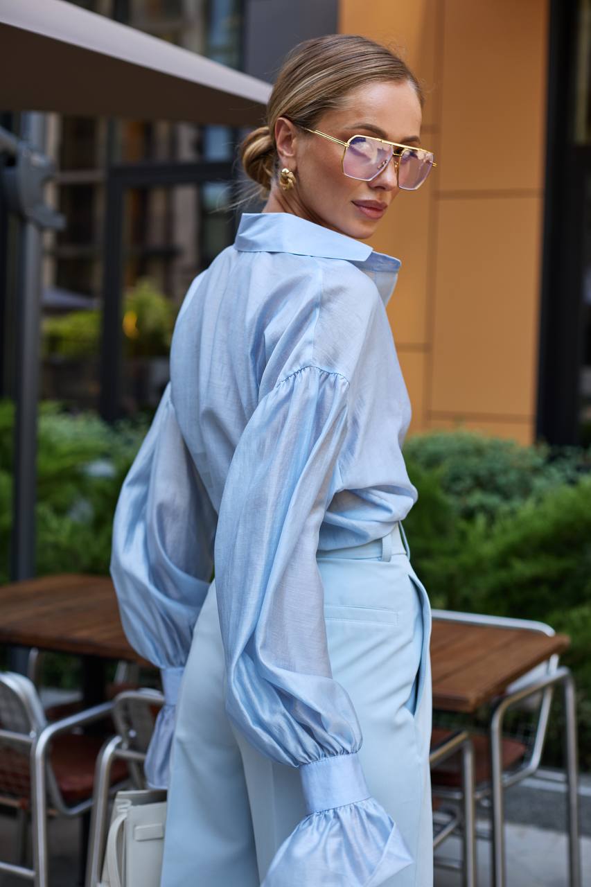 Woman wearing a light blue outfit with sunglasses in an outdoor setting
