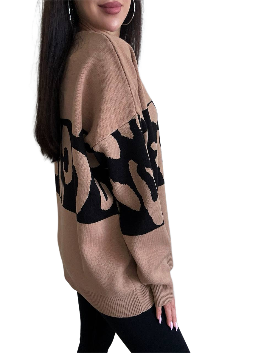 Beige sweater with black abstract patterns worn by a person on a white background