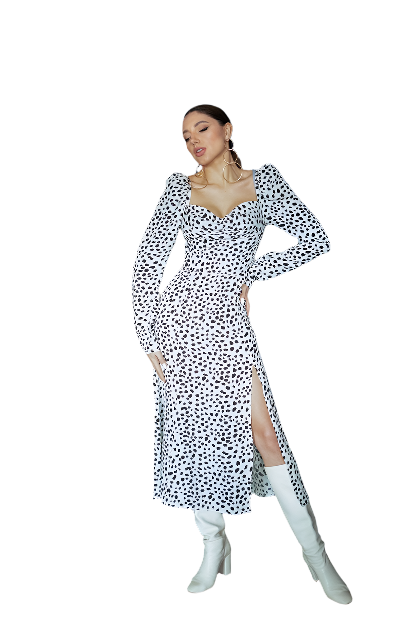 Woman wearing a black and white patterned dress with white knee-high boots on a white background