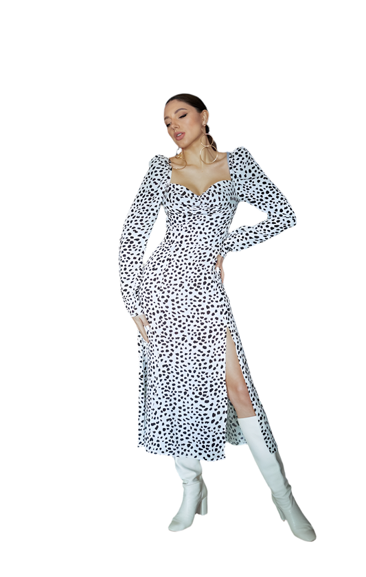 Woman wearing a black and white patterned dress with white knee-high boots on a white background