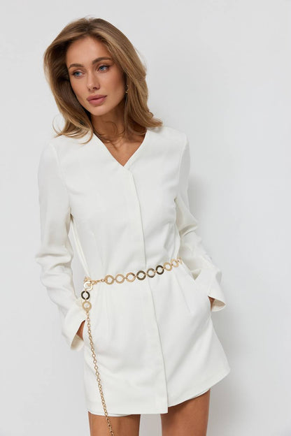 Woman wearing a white blazer dress with a belt against a plain background