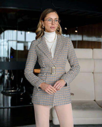 Woman wearing a patterned blazer and light pink pants in an indoor setting.