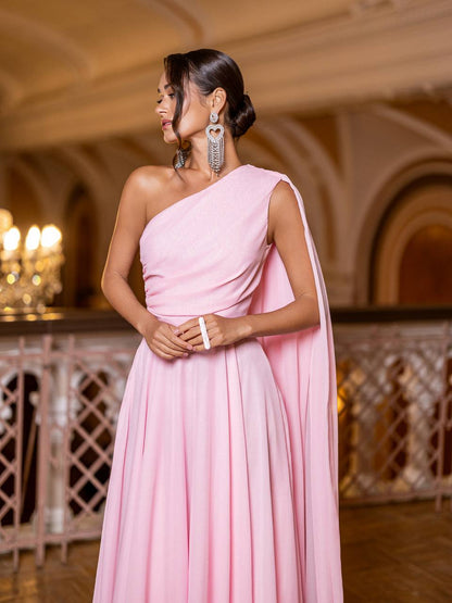 Woman in a pink one-shoulder gown standing in an elegant indoor setting.