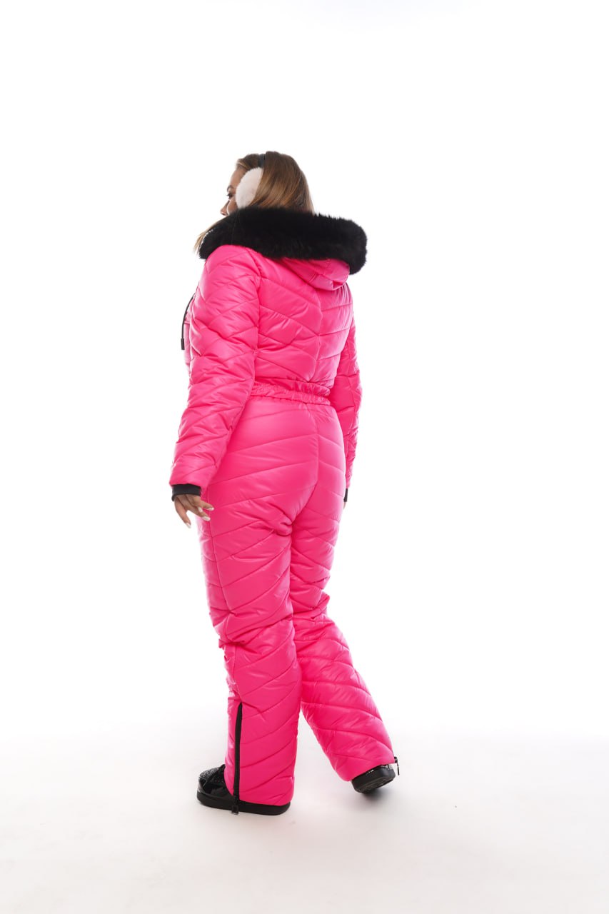 Person wearing a bright pink snowsuit with black fur trim on a white background