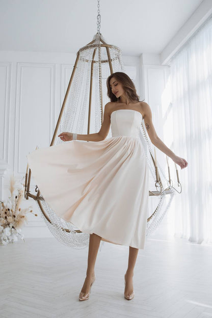 Woman in a white dress standing in a bright room with a decorative hanging chair.