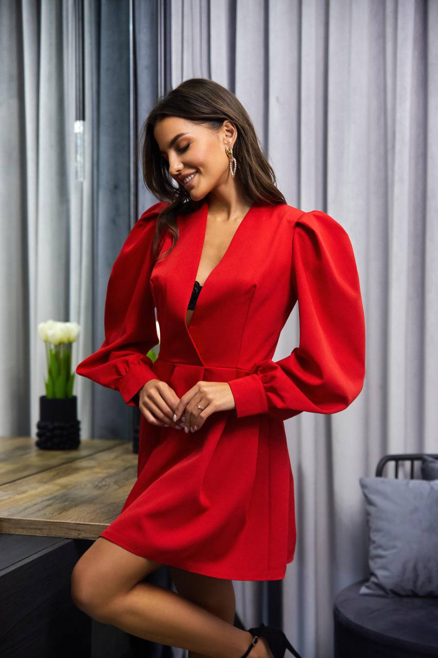 Woman wearing a red dress in an indoor setting with curtains and a table.
