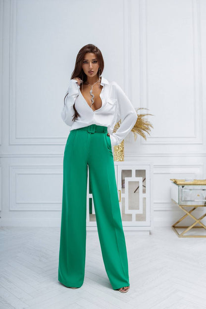 Woman wearing a white blouse and green pants in a stylish interior setting