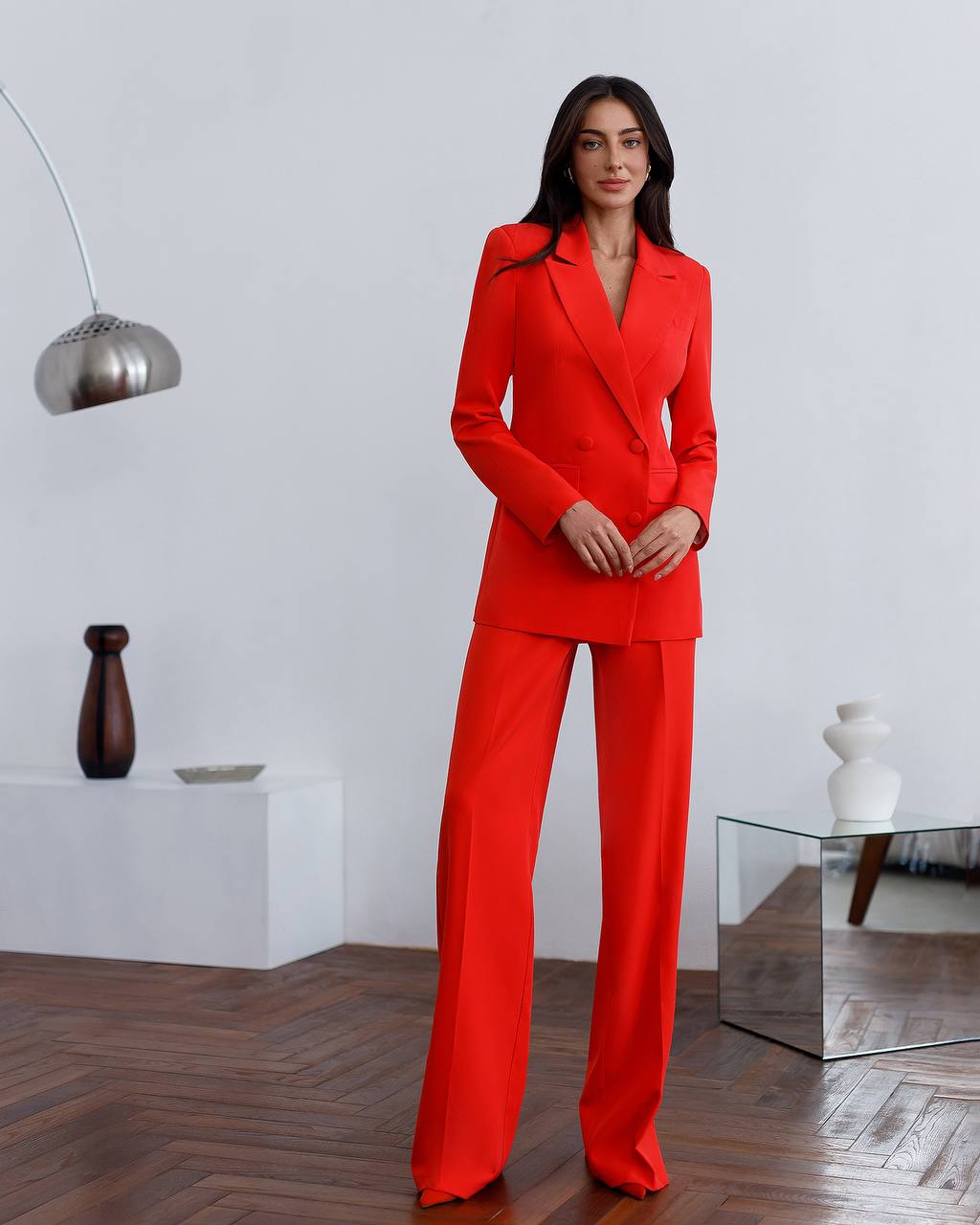 Woman wearing a red suit standing in a modern interior setting