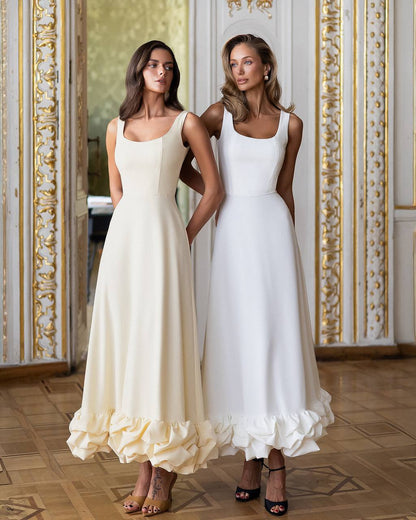 Two women wearing white dresses standing in a room with ornate decor.