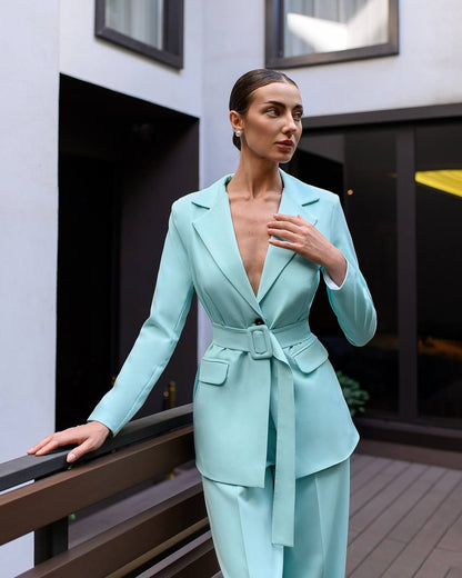 Woman wearing a light blue suit standing on a balcony.