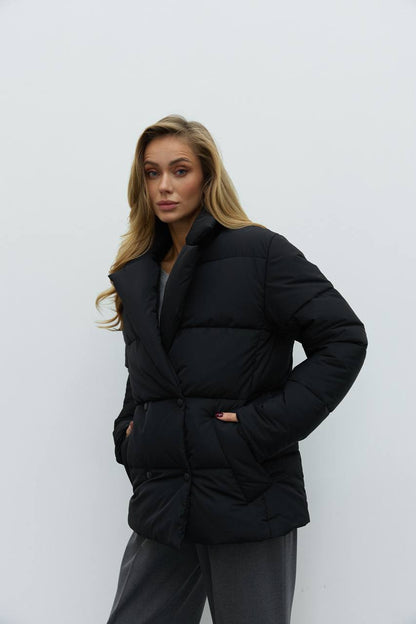 Woman wearing a black puffer jacket against a white background