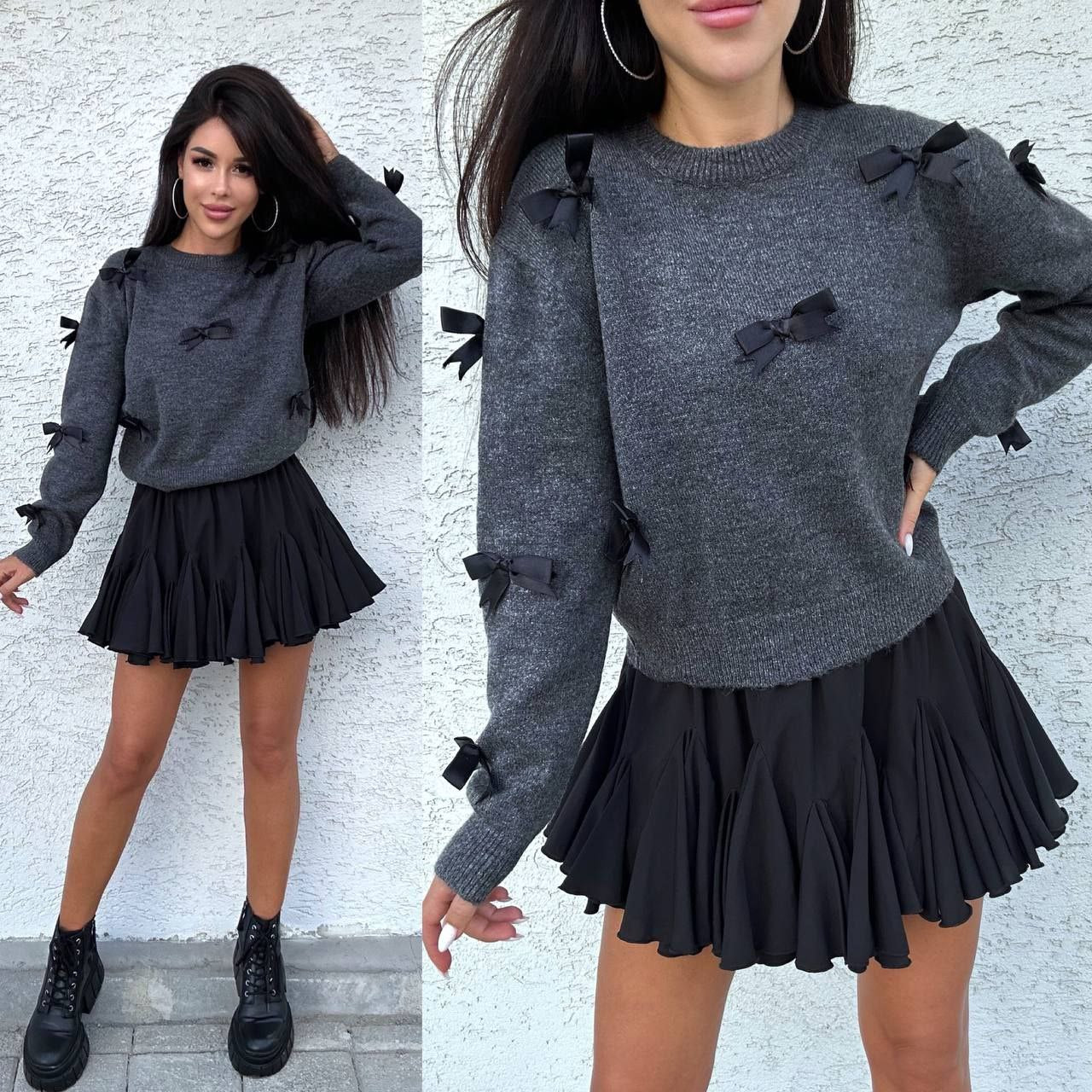 Woman wearing a gray sweater with black bows and a black skirt against a white wall.