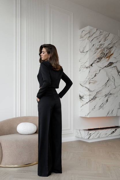Woman in a black outfit standing in a stylish room with marble wall art.