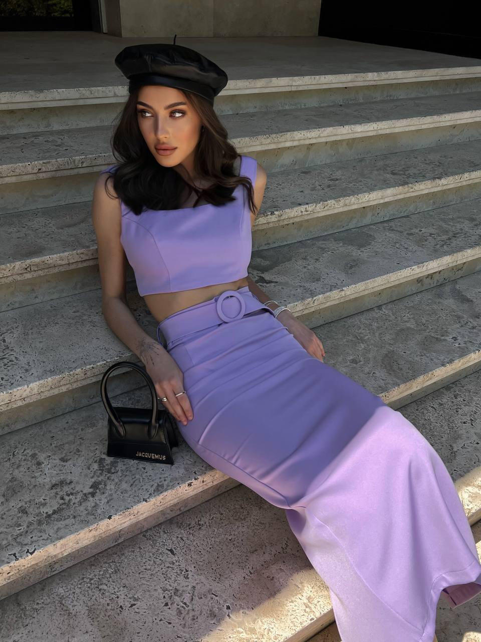 Woman in a lavender outfit sitting on stone steps.