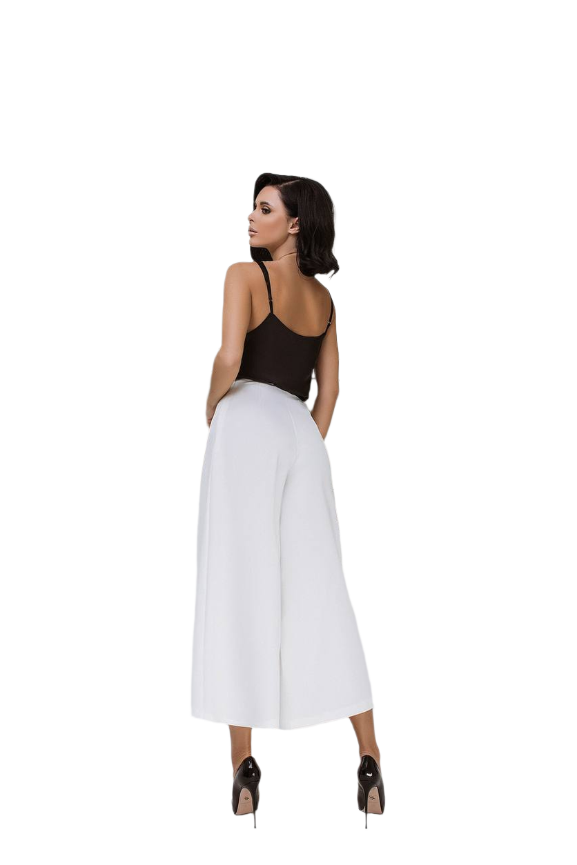 Woman wearing a black top and white wide-leg pants on a white background