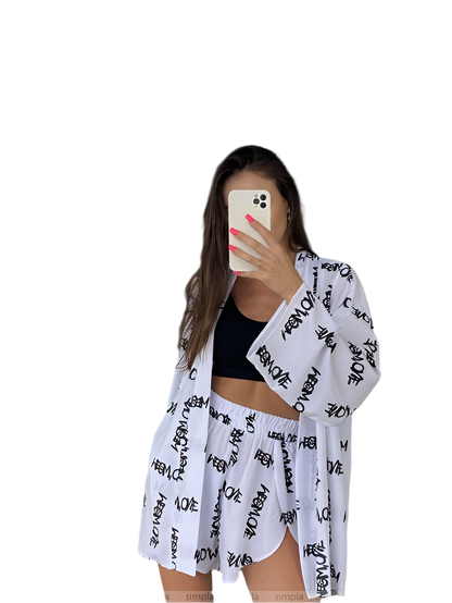 Woman wearing a white kimono with black text over a black top and shorts on a white background