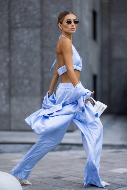 Woman in a light blue outfit walking outdoors with a blurred background