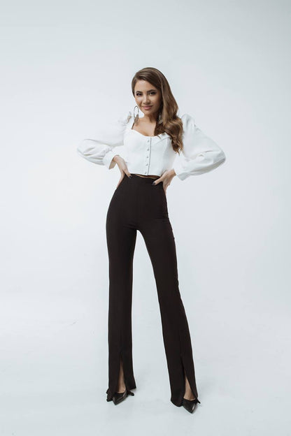 Woman wearing a white blouse and black pants on a white background