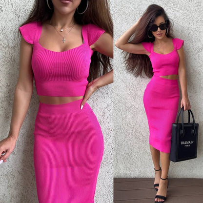 Woman wearing a bright pink two-piece outfit with a matching handbag.