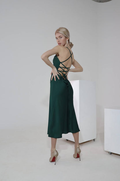 Woman wearing a green dress with strappy details in a minimalistic setting