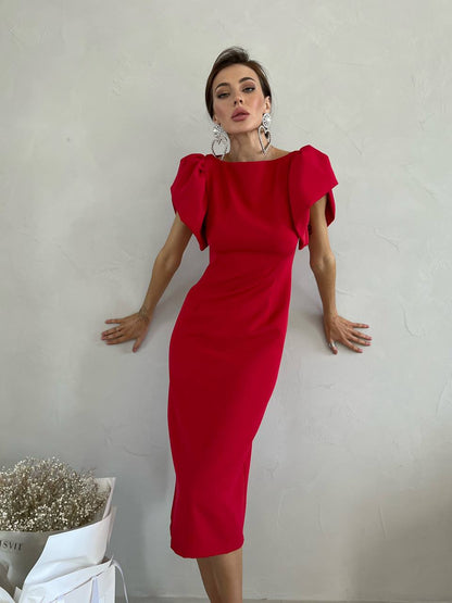 Woman wearing a red dress with puffed sleeves against a plain background